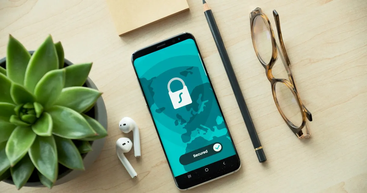 Smartphone met een hangslot op het scherm en de melding 'Secured', naast een bril en een plant op een bureau